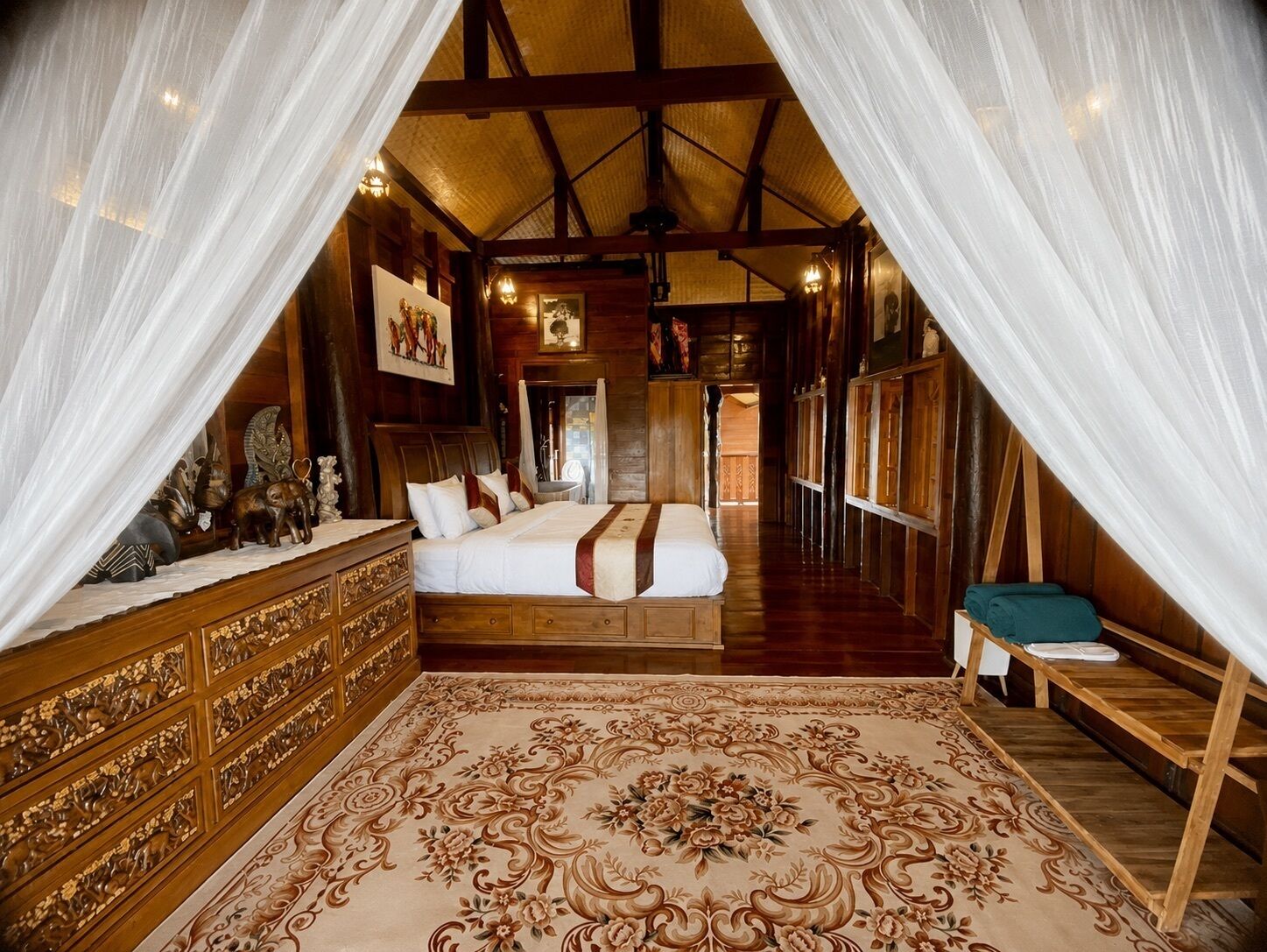 Una habitación con una cama grande, un aparador de madera y una alfombra decorativa.