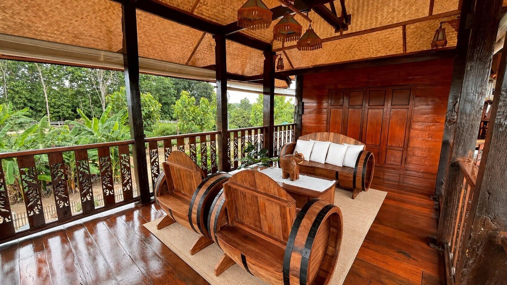 A wooden interior with a thatched roof, a wooden bench, a sofa, and a table.