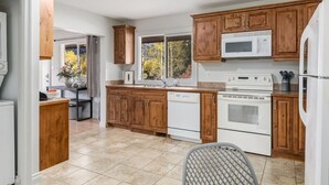A kitchen with wooden cabinets, a microwave, a stove, and a dishwasher. - 2BR Red Cedar Lodge near Banff w/ Mountain Views (Harvie Heights)
