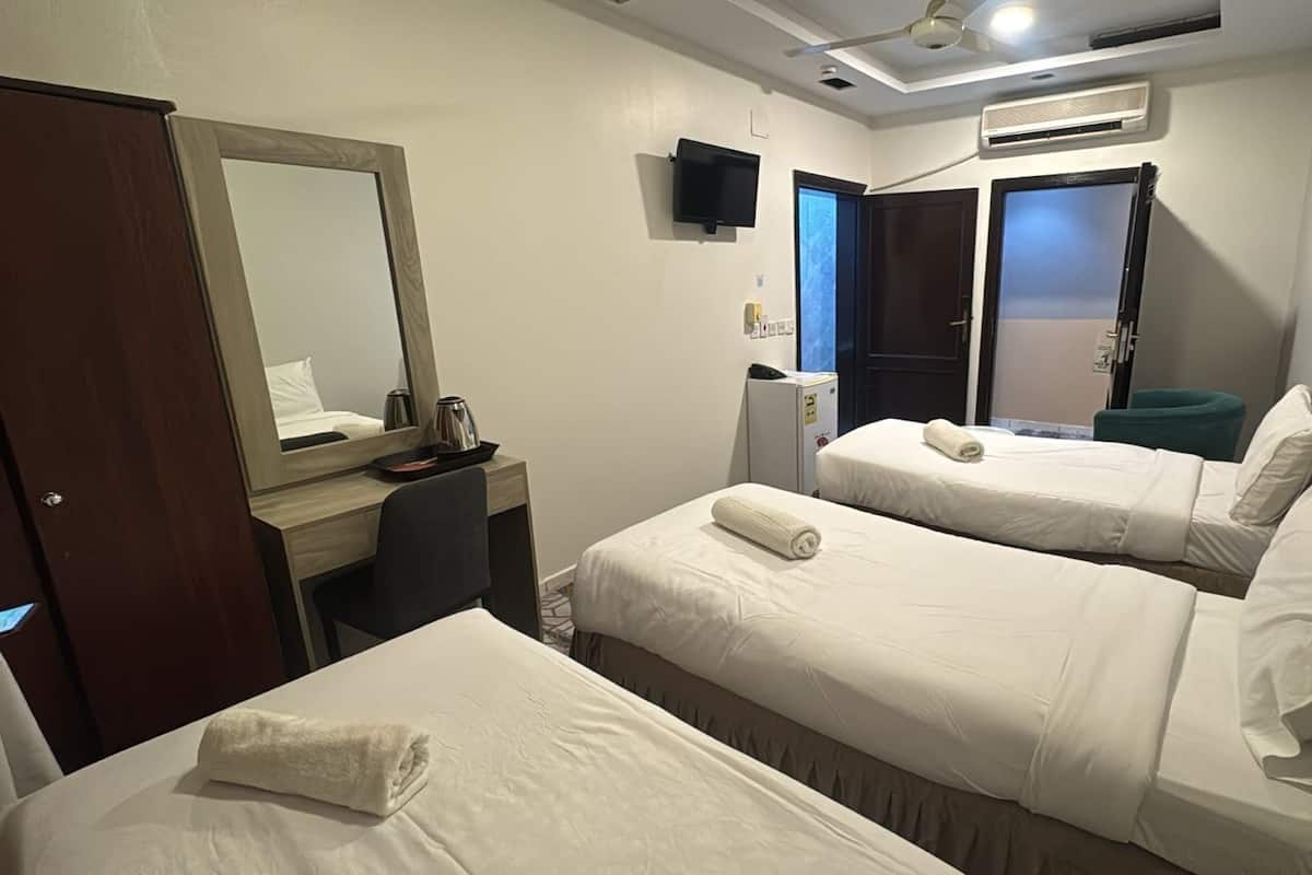 Une chambre d’hôtel avec deux lits, un bureau, un miroir, une télévision et un appareil de climatisation.