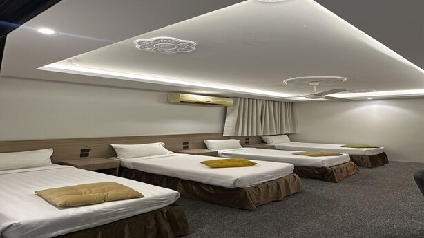 Een hotelkamer met vier enkele bedden, een plafondventilator en een modern design met inbouwverlichting.