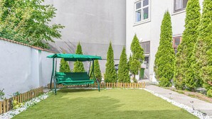 A neatly maintained garden with a green swing set, trimmed hedges, and a paved pathway. - Modern Cozy Studio With City Access (Vienna)