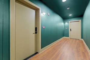 Un couloir aux murs de couleur turquoise, doté d’un plancher en bois et de deux portes.