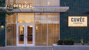 A modern building with a glass facade, a sign reading 'CUVÉE COFFEE,' and a balcony. - South Lamar Stay w/ Private Balcony | Pool, Terrace, On-Site Dining | The Code (Austin)