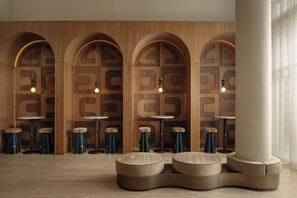 Un intérieur moderne avec des murs en bois, des niches en arc de cercle, des tables rondes et des tabourets.
