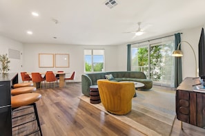 A modern living room with a sofa, chairs, a dining table, and a bar area. - Private Balcony | Resort Pool, Terrace w/ Views, On-Site Dining | The Code (Austin)