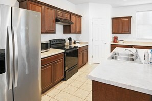 A modern kitchen with stainless steel appliances, wooden cabinets, and a white countertop. - 4BR Casa Grande Home | Game Table + Large Yard (Casa Grande)