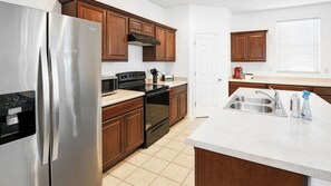 A modern kitchen with stainless steel appliances, wooden cabinets, and a white countertop. - 4BR Casa Grande Home | Game Table + Large Yard (Casa Grande)