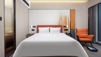 A modern hotel room with a large bed, a nightstand, a chair, and a large window.
