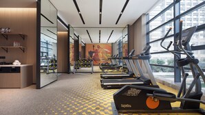 Une salle de sport équipée de tapis de course, de ballons d’exercice et d’un mur recouvert de miroirs.