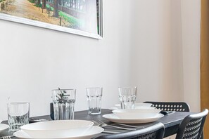 A dining table set with plates, glasses, and cutlery, with a framed picture on the wall. - Cozy 1BR Apt Next to Schöpfwerk Station (Vienna)