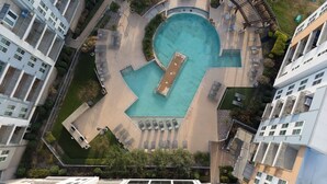Vista aérea de um edifício residencial moderno com piscina central, áreas de estar ao ar livre e vegetação circundante.
