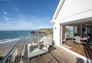 A balcony with a view of the ocean and a dining area with chairs and a table. - Seaside House is an exceptional coastal retreat offering panoramic views (Portreath)