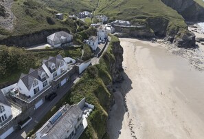 Un quartier résidentiel situé sur la côte, avec des maisons construites sur une falaise surplombant une plage de sable.