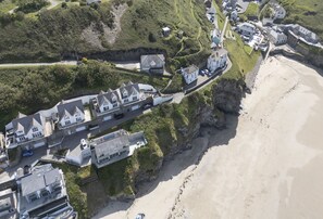 An aerial view of a coastal property with multiple buildings, a beach, and a cliffside. - Seaside House is an exceptional coastal retreat offering panoramic views (Portreath)
