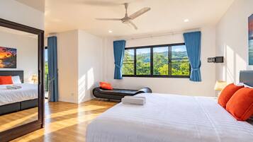 Una habitación de hotel moderna con una cama grande, un ventilador de techo, una ventana con cortinas y vistas a zonas verdes.