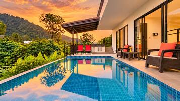A modern outdoor pool area with a clear view of the surrounding greenery and hills.