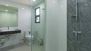 Un baño moderno con ducha de vidrio, lavamanos blanco y retrete.
