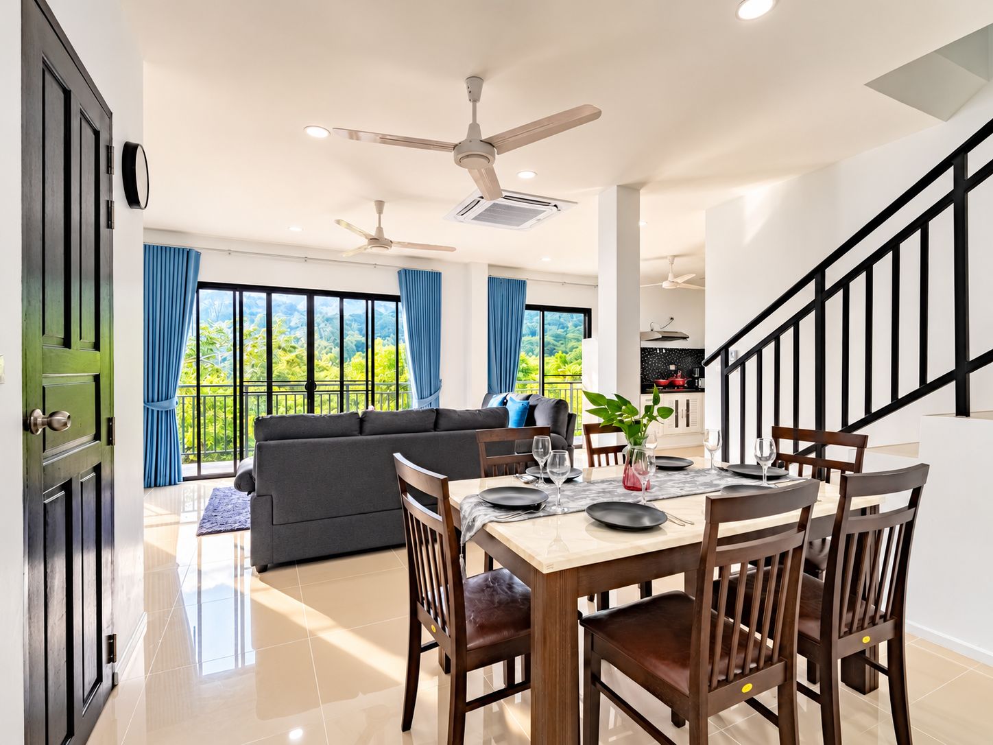 A modern interior with a dining area, sofa, and staircase.