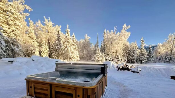 Un jacuzzi en un entorno boscoso nevado.