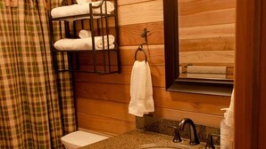 Ein Badezimmer einer Holzhütte mit Toilette, Waschbecken und Handtuchhalter.