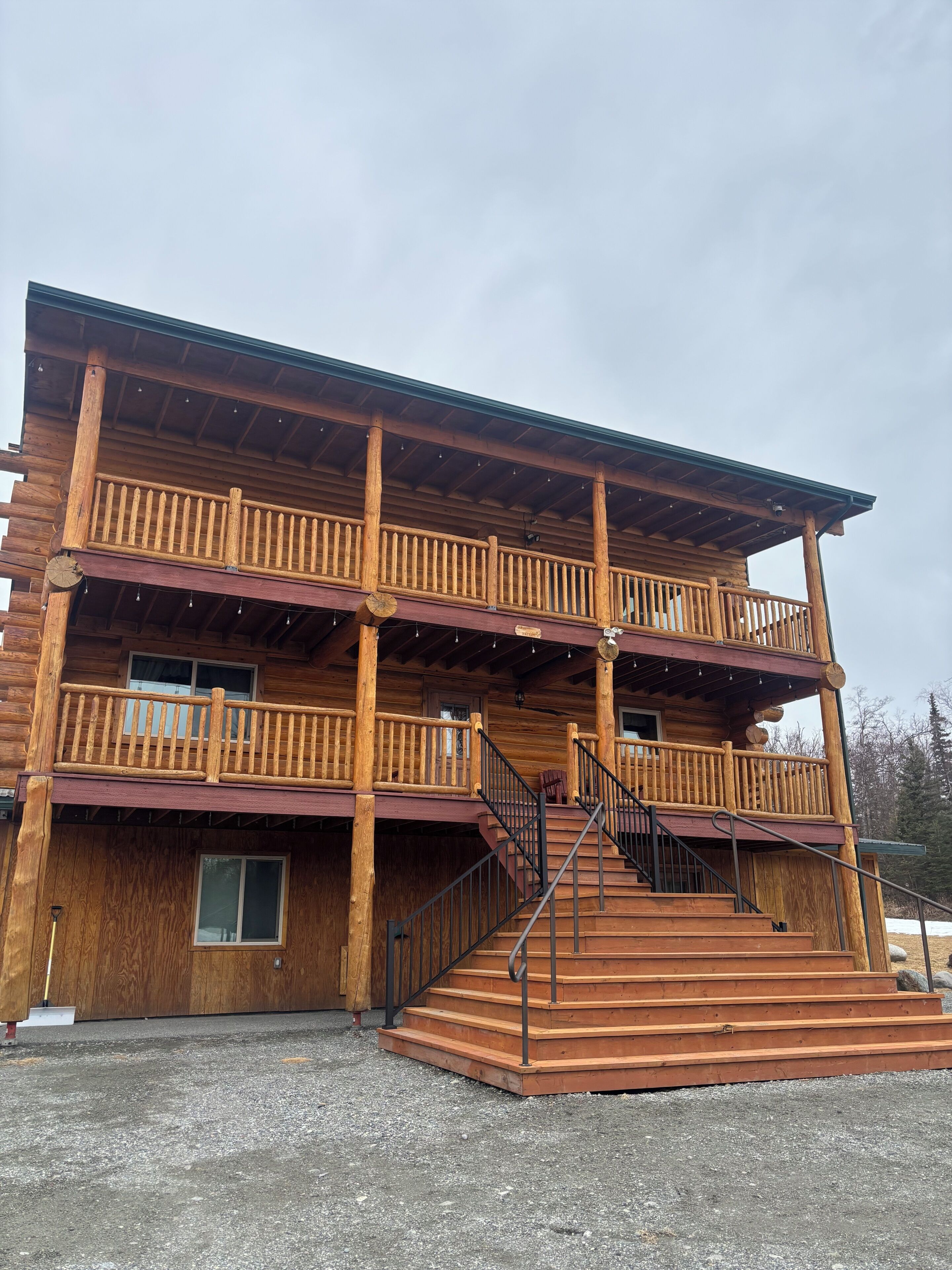 A multi-story wooden building with a balcony, stairs, and a covered porch area.