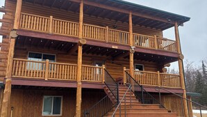 Un bâtiment en bois à plusieurs étages, doté d’un balcon, d’un escalier et d’une véranda couverte.
