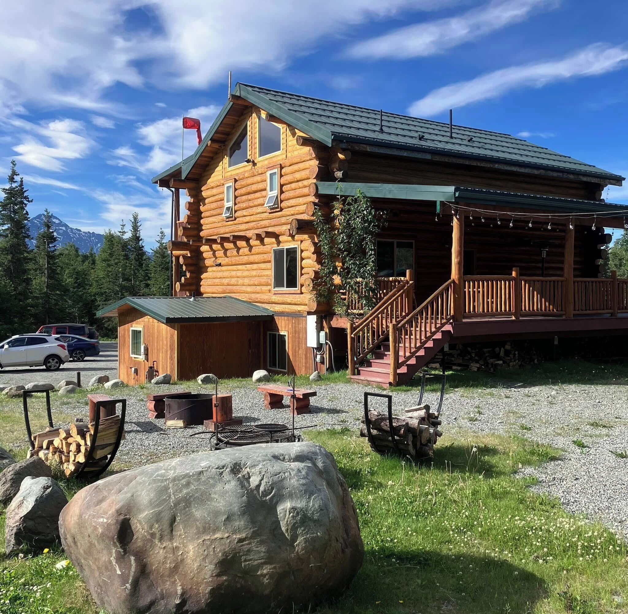 A log cabin with a porch, a staircase, and a view of a mountain.