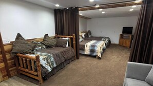 A bedroom with two beds, a grey sofa, and a TV. - Fisherman's Suite~Jetted Tub~Optional Indoor Sauna@ Alaska Knotty Pine B&B (Lazy Mountain)
