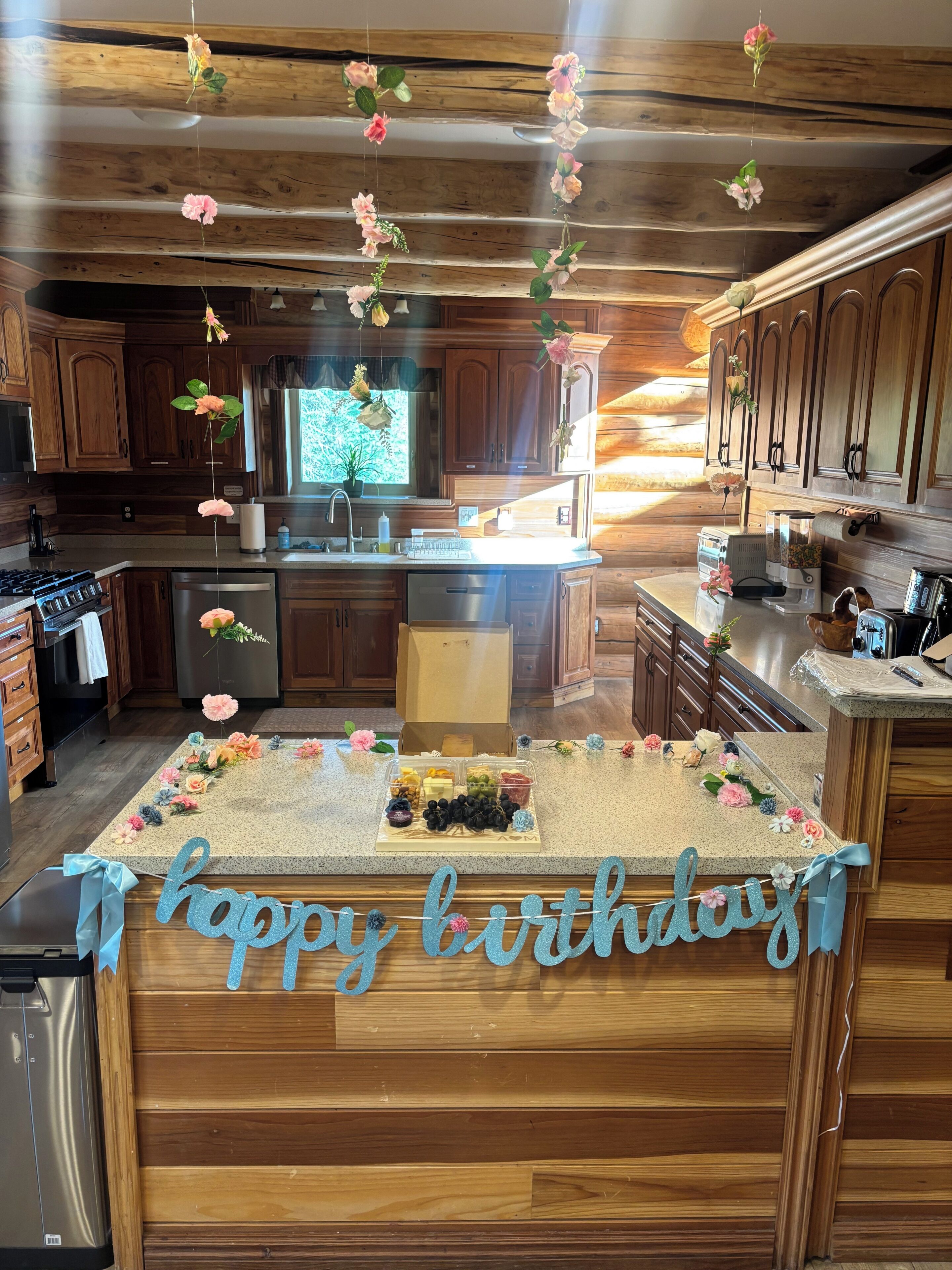 A kitchen with wooden cabinets, a granite countertop, and a 'happy birthday' sign.