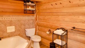A wooden cabin bathroom with a bathtub, toilet, and a towel rack.