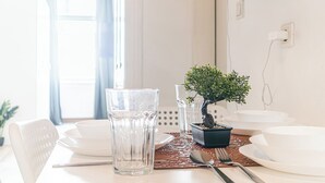 A dining table set with white plates, clear glasses, and a small potted plant. - Beautiful 2BR Apt Near Meidling Station (Vienna)