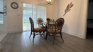 Uma sala de jantar com uma mesa e cadeiras de madeira, um candelabro e um relógio de parede.