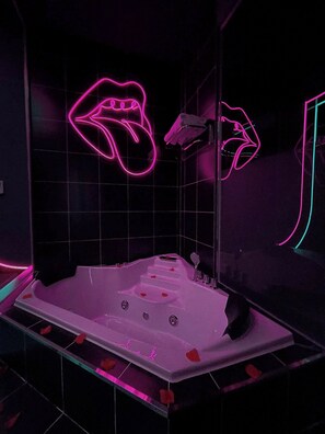 A modern bathroom with a freestanding bathtub, a hand-shaped neon light, and a grid-patterned wall. - 6 SENSES HOTEL (Hanoi)
