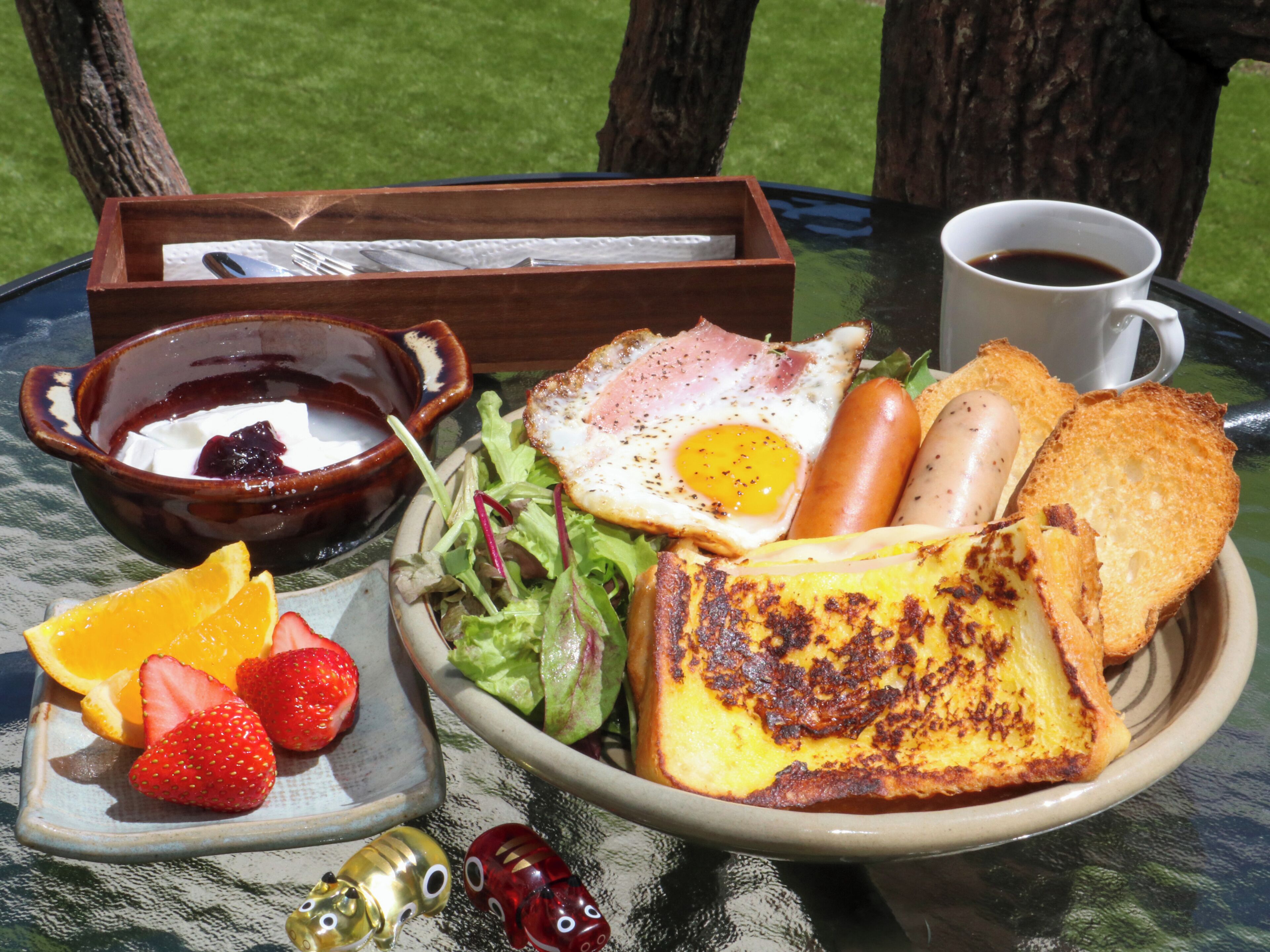 A meal with toast, eggs, sausages, and salad on a table with a glass top.
