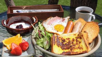A meal with toast, eggs, sausages, and salad on a table with a glass top.