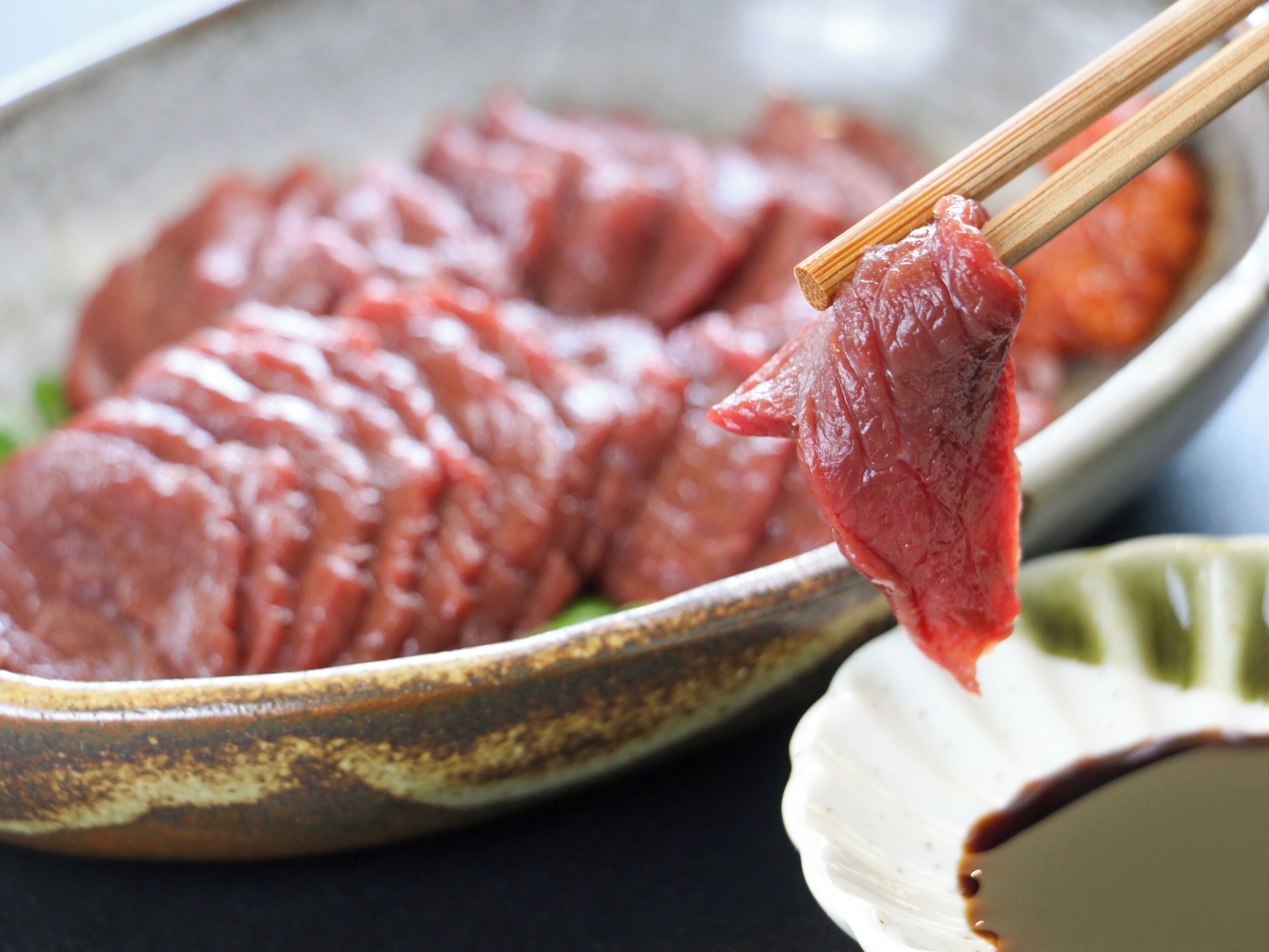 A plate of raw meat with chopsticks.