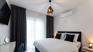Une chambre d’hôtel moderne, dotée d’un grand lit, d’un bureau avec une chaise, d’une télévision et d’un luminaire au plafond.