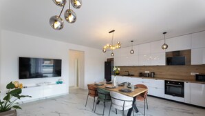 Une cuisine moderne dotée d’un plan de travail en bois, d’appareils électroménagers intégrés et d’un coin repas avec un sol en marbre.