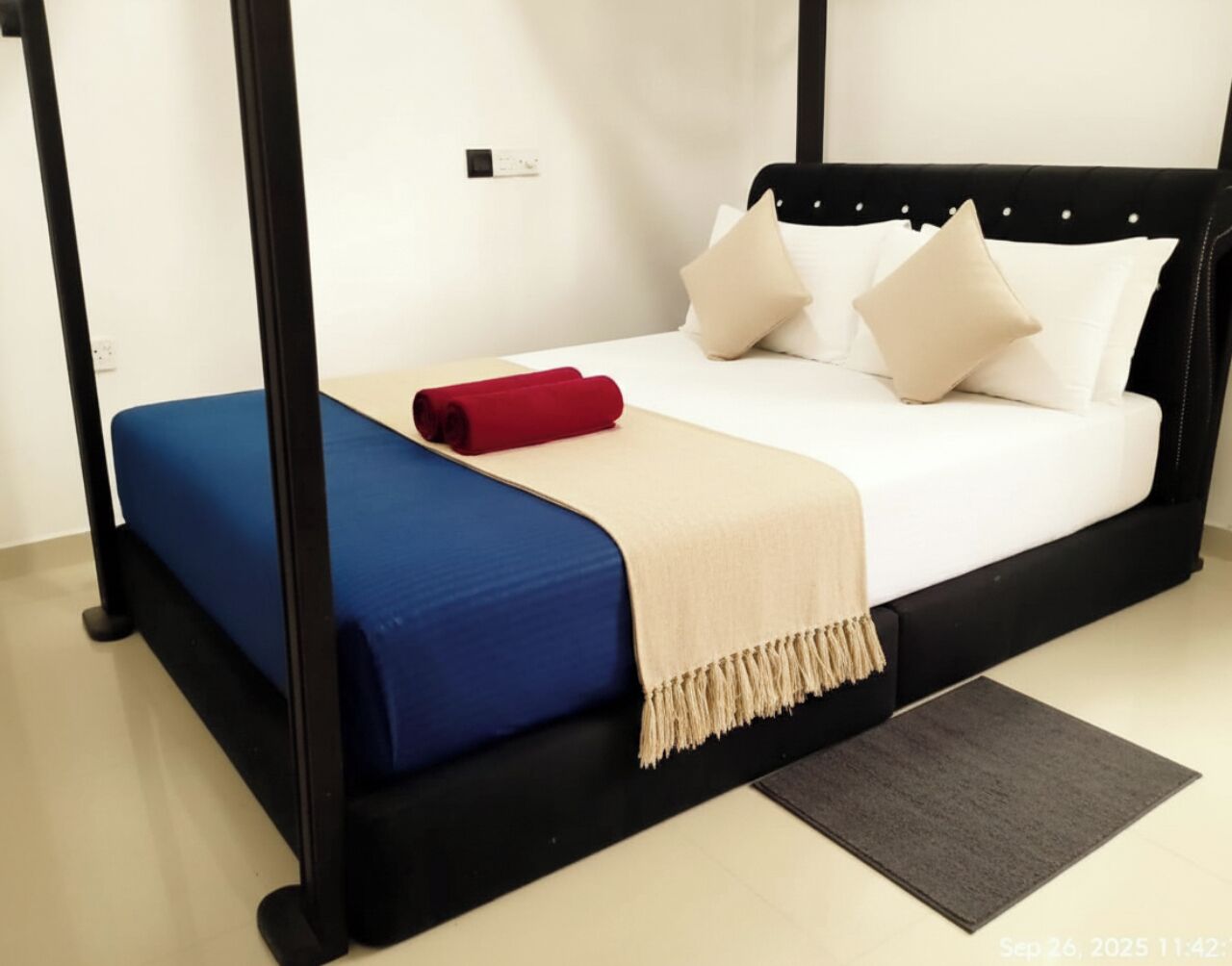 Ein Himmelbett mit blauer Matratze und einer beigen Tagesdecke.