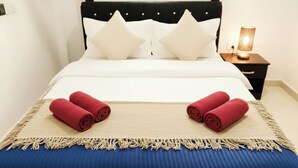 Ein ordentlich gemachtes Bett mit weißen Leinen, zwei weißen Kissen und zwei roten Handtüchern.