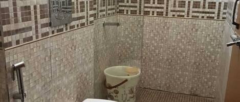 A small bathroom with a toilet, a shower, and a tiled wall.