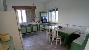 A compact kitchen with green cabinets, a dining table, and a refrigerator. - At 9 minutes from Milan Malpensa I rent bed with breakfast, pets allowed (Oleggio)