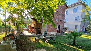 A courtyard with a brick building, outdoor seating, and a small palm tree. - At 9 minutes from Milan Malpensa I rent bed with breakfast, pets allowed (Oleggio)