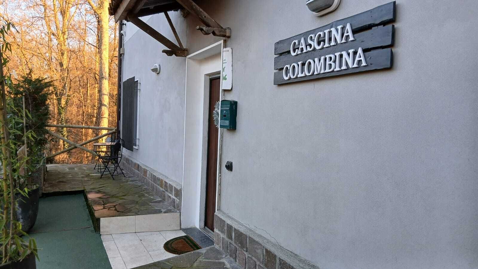 Ein Gebäude mit einem Schild, auf dem „CASCINA COLOMBINA“ steht, und einer kleinen Außenbereich-Sitzgelegenheit mit Tisch und Stühlen.