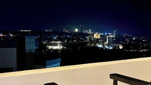 Un balcón con vistas a una ciudad iluminada de noche.