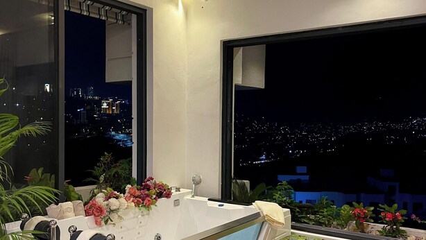 Un baño moderno con una bañera grande, una ventana con vistas a la ciudad y plantas en macetas.