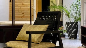 Una sala moderna con una silla negra, un separador de madera y un espejo grande.