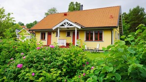 A yellow house with a red-tiled roof, surrounded by lush greenery and pink flowers. - 8 Person Holiday Home in Adelso (Adelso)