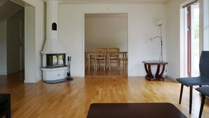 A spacious living room with a fireplace, wooden flooring, a dining area with chairs, and a modern chair. - 8 Person Holiday Home in Adelso (Adelso)